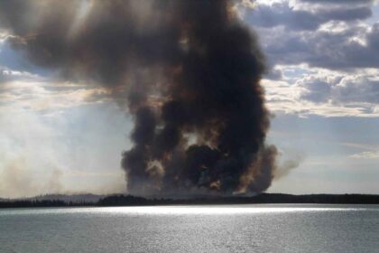 Thick wildfire smoke hanging over a forested hillside